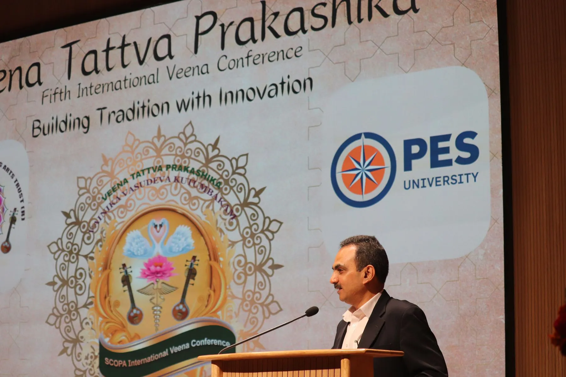 Speaker before 'Veena Tattva Prakashika – Fifth International Veena Conference: Building Tradition with Innovation' backdrop