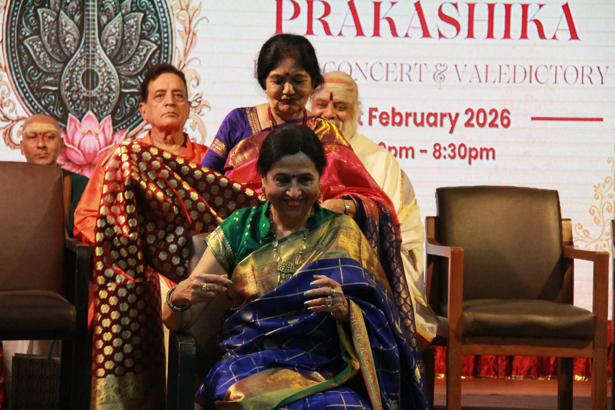 An honoree receiving a shawl on stage in front of the final concert and valedictory backdrop