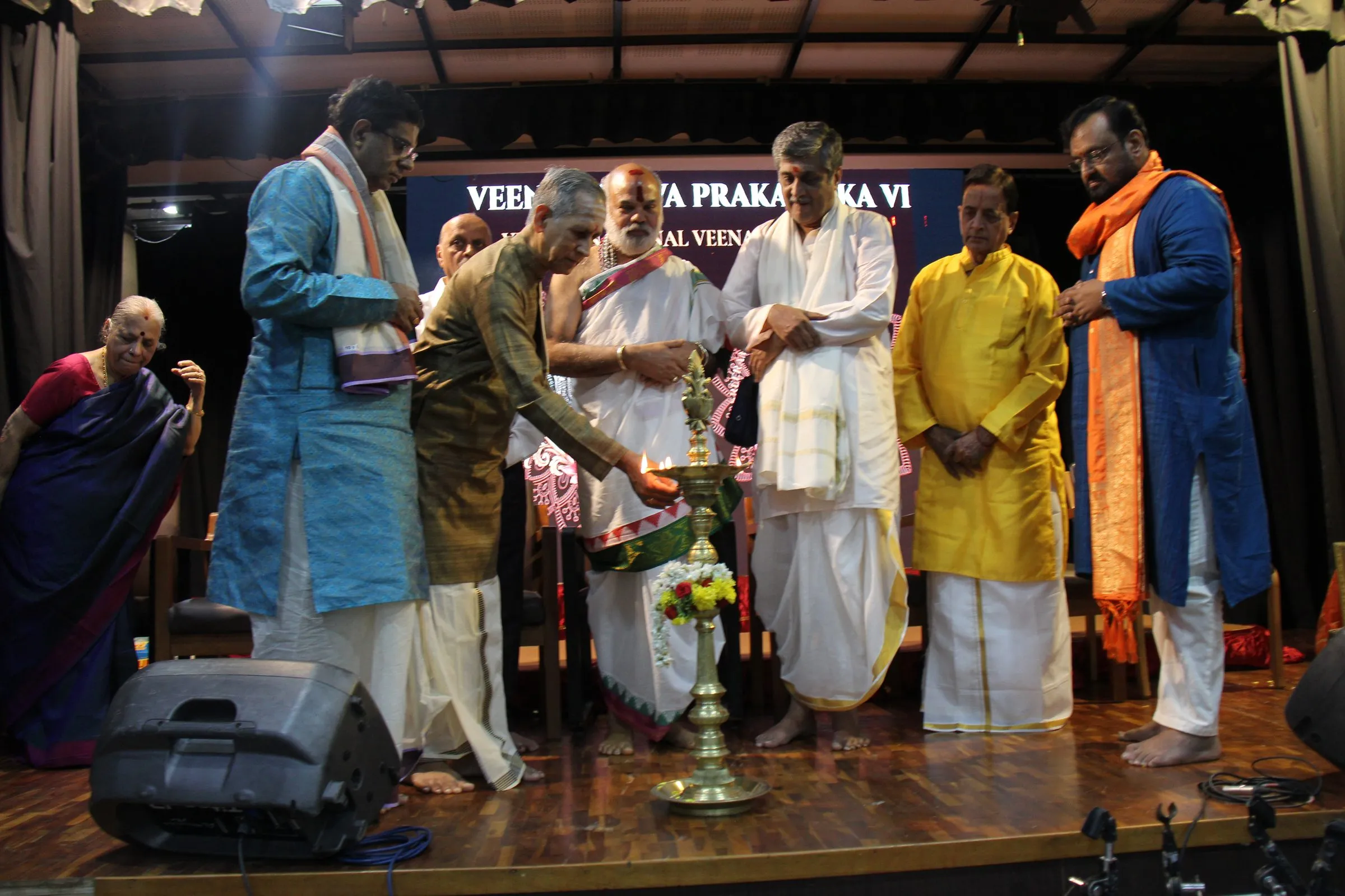 Guests lighting the ceremonial lamp on stage beneath the VTP VI banner
